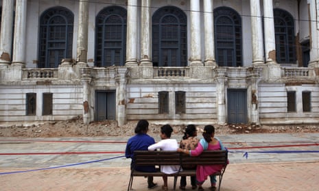 Nepalese people sit on a bench in front of damaged buildings at the Basantapur Durbar Square in Kathmandu, Nepal, Monday, June 15, 2015. Nepal on Monday reopened most of the cultural heritage sites that were damaged in a pair of devastating earthquakes, hoping to lure back foreign tourists. (AP Photo/Niranjan Shrestha)