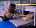 A researcher sitting at the side of a medical scanning machine with a swaddled baby inside