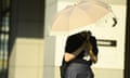 A person walks on the street protecting herself from the sun with a parasol and using a handheld fan in the late of afternoon on 5 July 2024, in Tokyo, Japan. The capital of Japan is swept by intense heatwave with temperatures above 35 degrees Celsius in Tokyo.