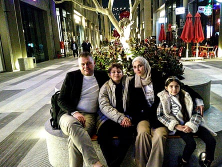 The family sit in a pedestrianised street, the kids smiling