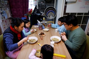 The children eat lunch with their parents at their home.