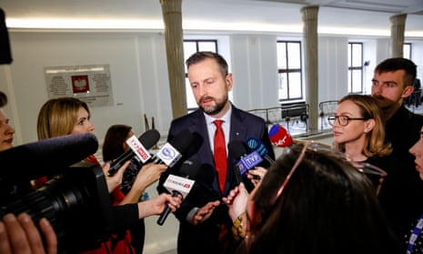 Władysław Kosiniak-Kamysz in a suit and tie talking to a gaggle of TV or radio reporters with microphones
