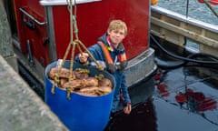 A young man loads a bucket of crabs off a fishing trawler