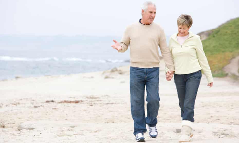 Older couple enjoying a stroll along the beach and holding hands.