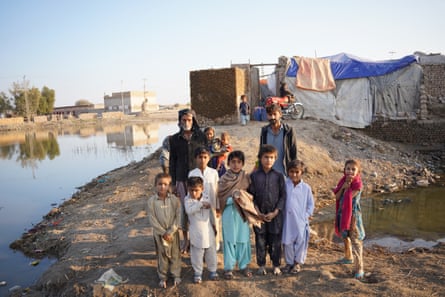 Ghulam Rasool, 72 ans, se tient avec son fils et ses petits-enfants devant la maison en ruine qu'ils tentent de réparer sans aucune aide de l'État.