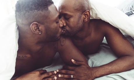 Stock image of a gay couple kissing and make sex in the bed