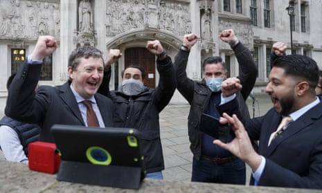 Uber drivers celebrate as they listen to the court decision on a tablet computer outside the supreme court in London