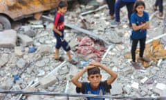 Palestinian children collect belongings from the rubble after Israeli attacks in Rafah.