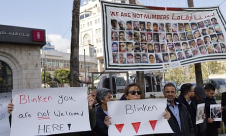 Protesters hold up signs protesting Blinken’s visit to the West Bank