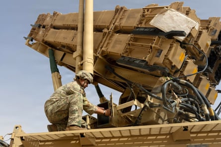A soldier crouches down while working on the missile system