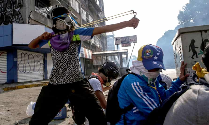 A protester takes aim at riot police with a sling shot during anti-government protests in Caracas, May 2017.