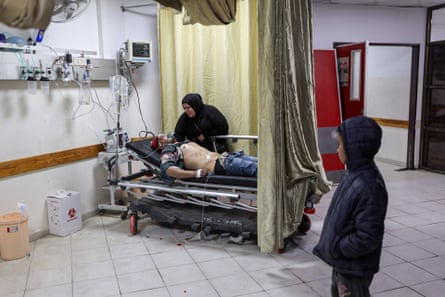 A woman tries to comfort an injured man, as a child watches them at the Indonesia hospital in Bait Lahia in Gaza on 22 March 22, 2025