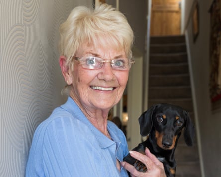 Naylor smiles as she stands posing in her doorway holding a small dog