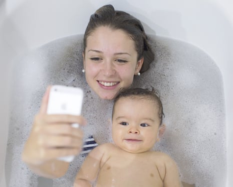 Mother using smartphone to photograph herself and baby