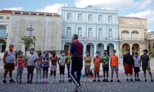 A teacher at a Cuban school explains the dangers of Covid to his students.