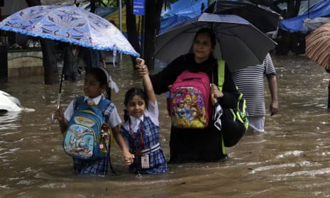 Girls and their mother wade through a flooded street in Mumbai