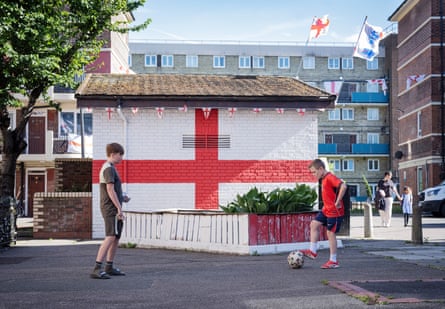 Two boys kick a football in front of a wall painted with a huge St George’s cross