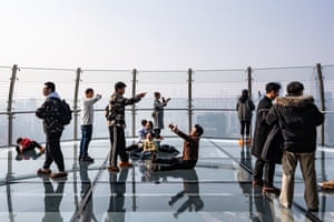 People standing on an observation deck with a glass floor take photos