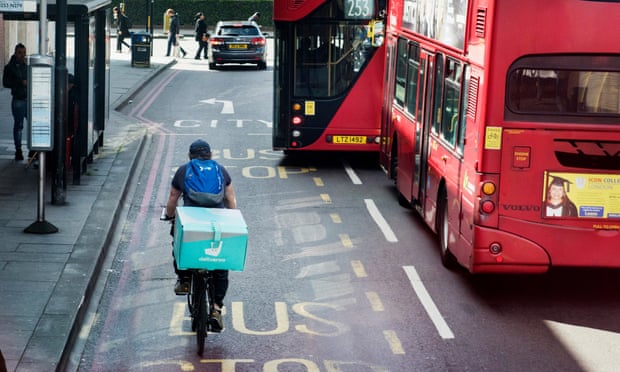 Deliveroo rider flanked by London double-decker