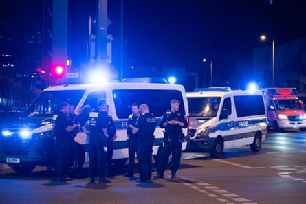 Police officers stand outside multiple police vehicles at night