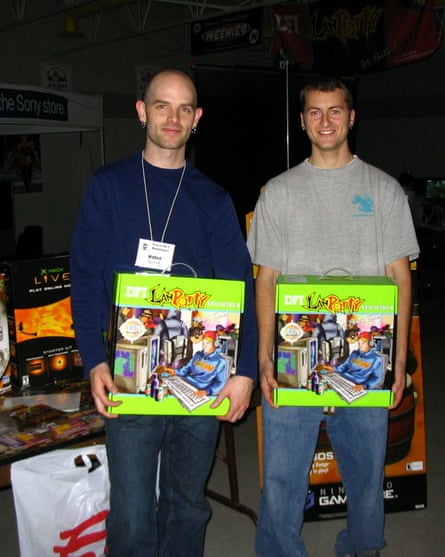 Two young men standing in a dark space holding boxes saying Lan Party