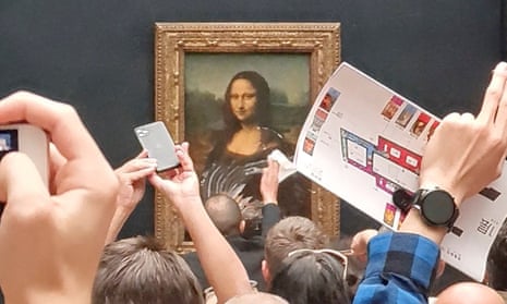 A gallery employee tries to wipe off the cream smeared on the protective glass of the Mona Lisa at the Louvre in Paris