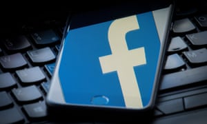 Facebook logo on iPhone resting on keyboard