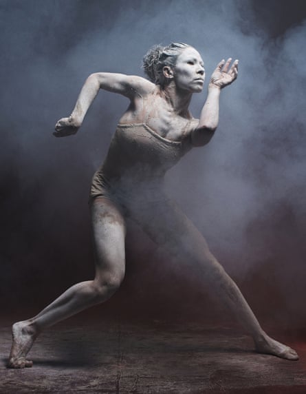 A woman covered in ochre in a contorted position