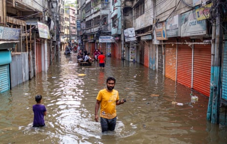 People walk through a flooded street in Dhaka, Bangladesh, after the passing of Cyclone Sitrang. 