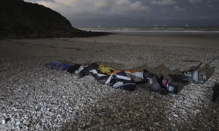 Lifejackets, sleeping bags and a damaged inflatable small boat on the sand