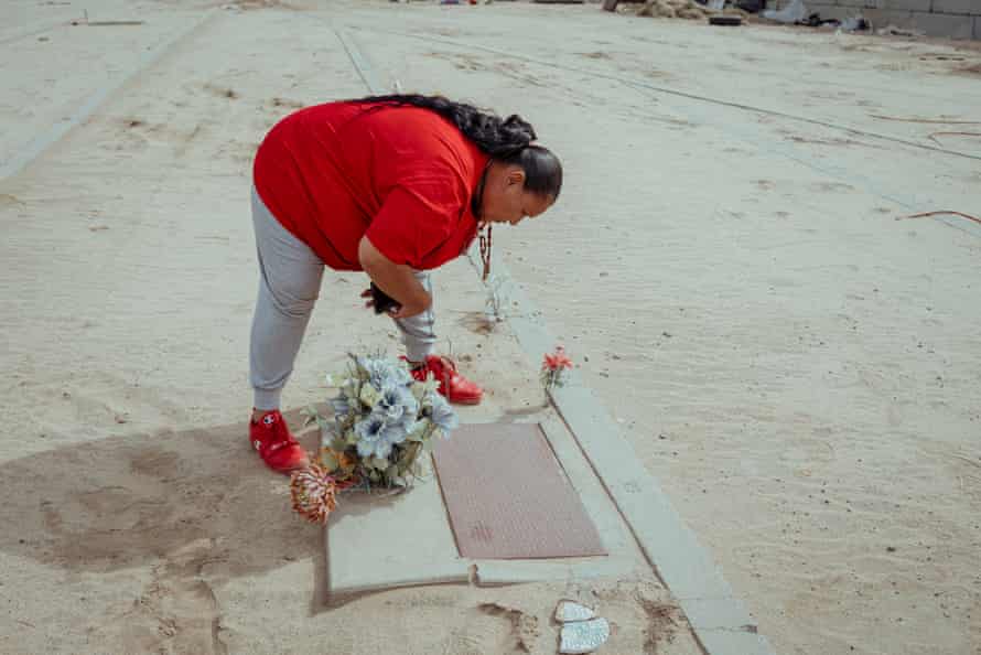 A woman wearing red looks down a memorial plaque