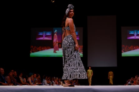 A model wearing a black and white printed dress and turban on the runway