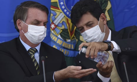 Luiz Henrique Mandetta offers President Jair Bolsonaro some anti-bacterial hand gel in Brasília on 18 March 2020.