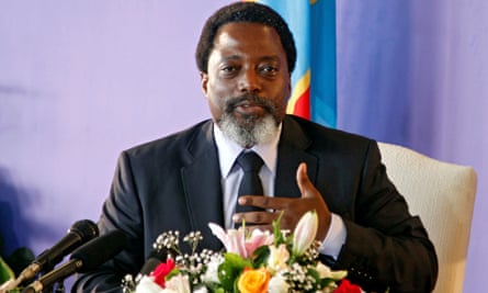 Joseph Kabila speaking to the camera, sitting down at a table behind a bouquet of flowers