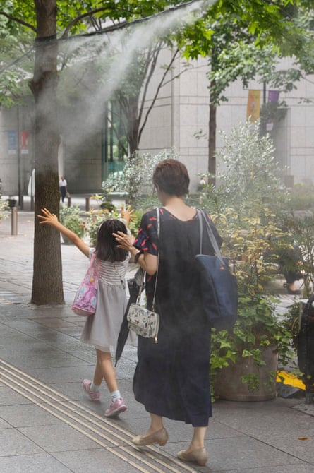 Pedestrians in Tokyo walk under cooling water sprays.