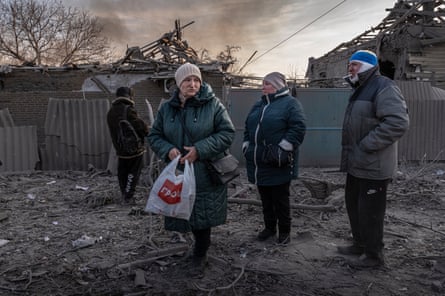 Four people observe the smouldering ruins of a house
