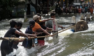 People struggle to cross a torrent of flood water in Kelaniya, on the outskirts of Colombo