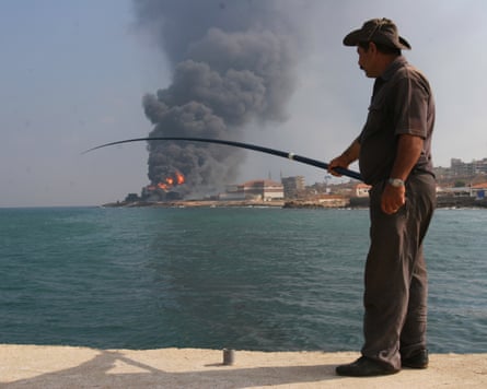 A fisherman in front of Lebanon's Jiyeh power station, ablaze after an Israeli strike during the Lebanaese war in 2006