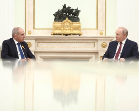 Nikol Pashinyan and Vladimir Putin sitting at a large, highly polished table