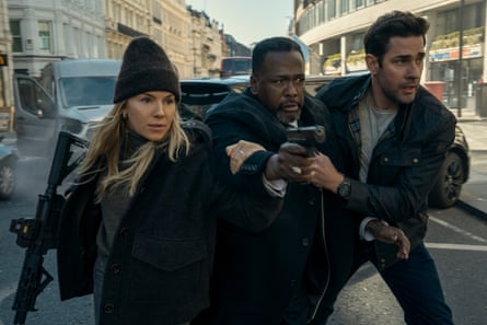 A woman and two men on a street with guns