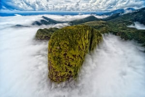 O topo de uma montanha está cercado por nuvens