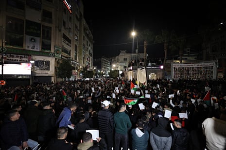 People stand holding Palestinian flags and a large banner can be seen in the background with the words ‘we are not numbers’