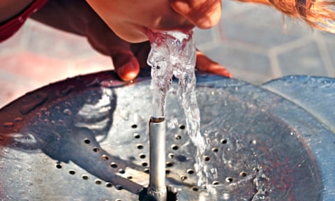 child drinks from water fountain