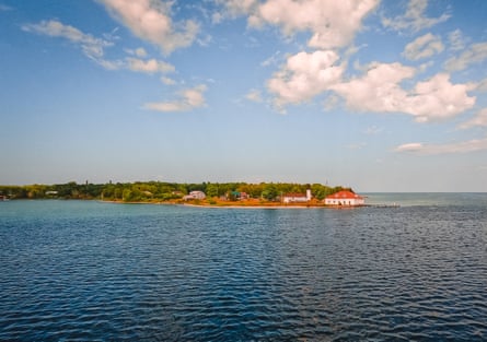 An island surrounded by lake water below blue cloudy sky