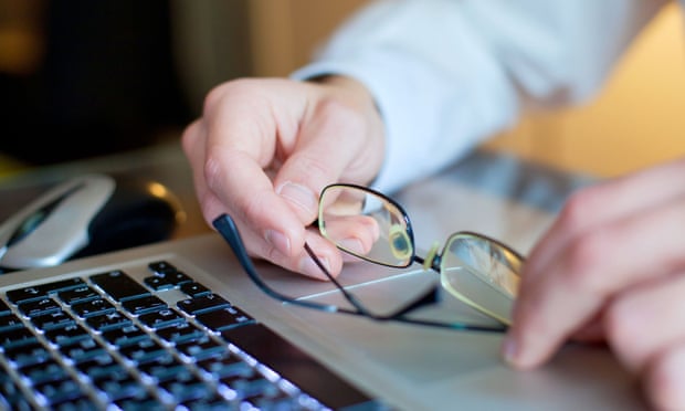 A man's hands and glasses on a laptop
