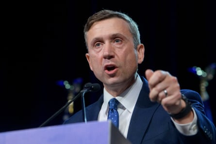 a man in a suit and tie speaks into a microphone