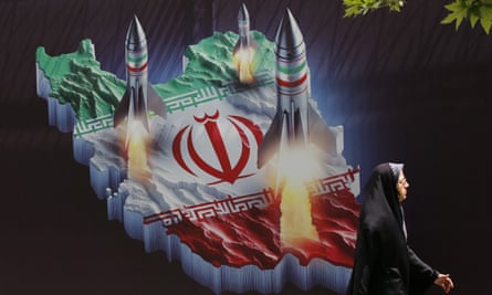 A woman walks past an anti-Israel banner carrying pictures of Iranian missiles in Tehran