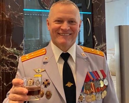 A smiling Col Yuri Khrameev in heavily decorated military uniform, holding a drink