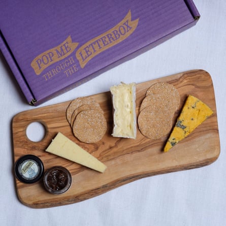 Butlers Farmhouse Cheeses Perfect British Cheeseboard with Crackers & Chutney. The cheese and condiments are displayed on a wooden board with the purple packaging box behind.