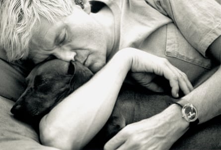 Black and white, close-up pic of Hockney, who looks to be snoozing, with his arms wrapped around a dachshund